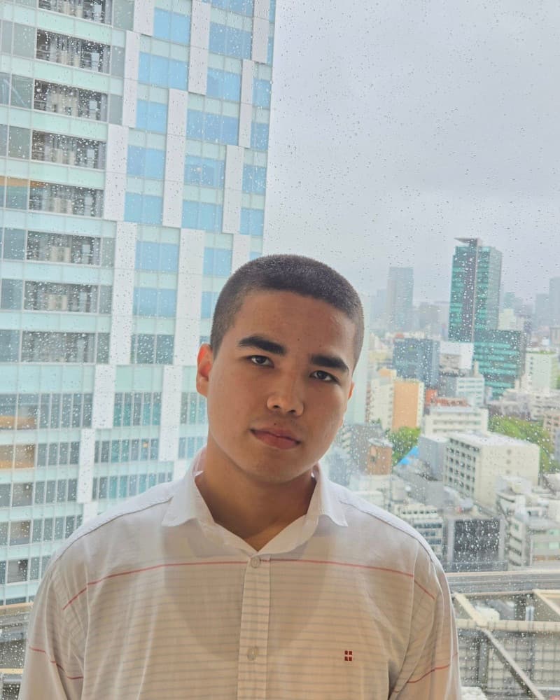 Azamat Erkinov in front of a rainy Tokyo skyline